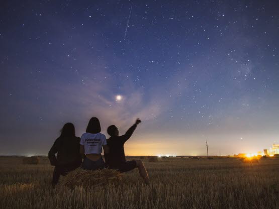 Ungdomar som pekar upp mot stjärnhimmel
